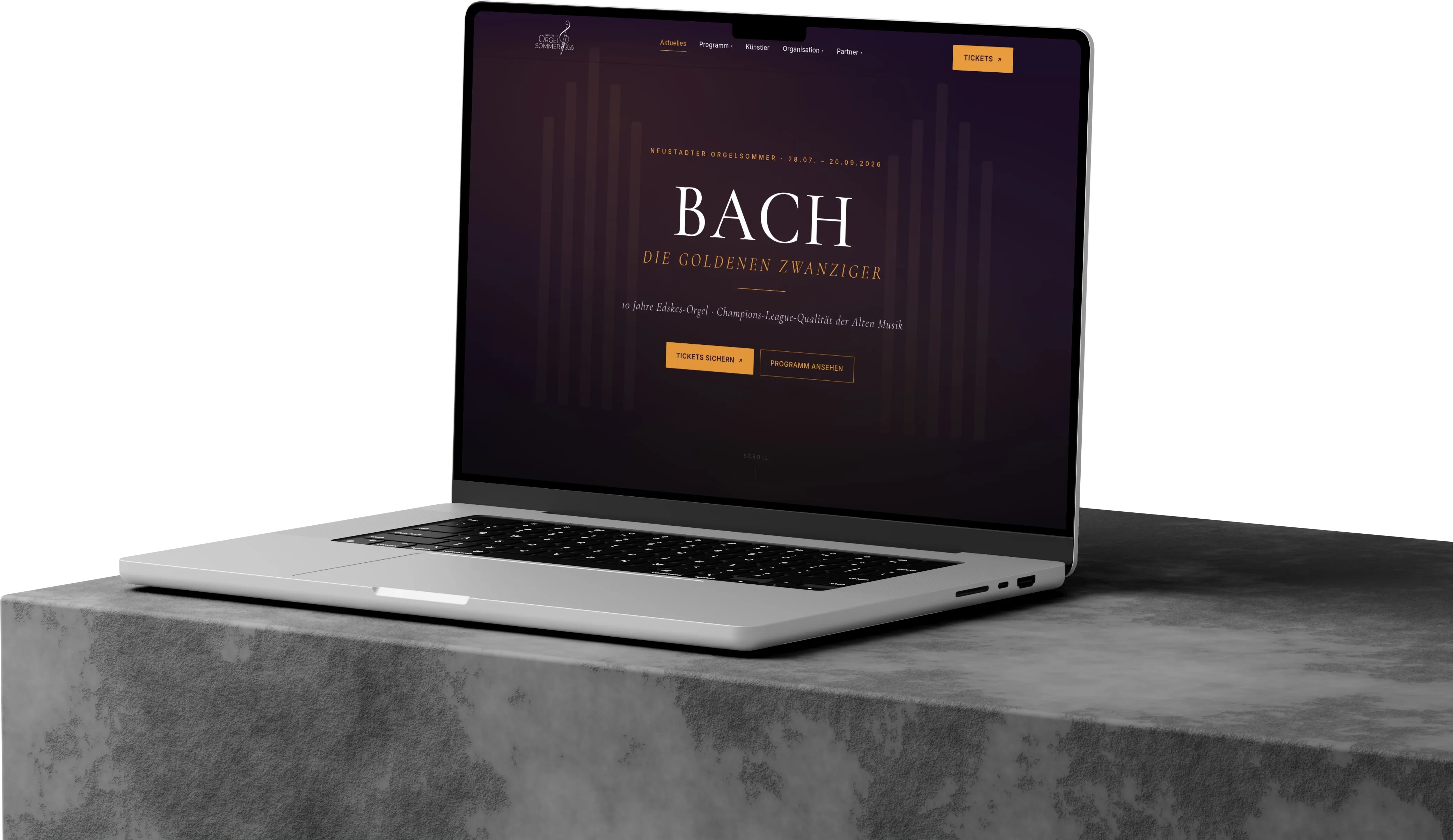MacBook auf einem Betonsockel mit der Startseite des Neustadter Orgelsommers 2026 – „BACH · Die goldenen Zwanziger“